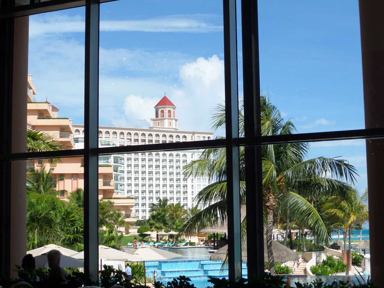 The view from inside the resort's dining room — palm trees, pools, and the Caribbean stretching to the horizon.